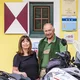 Motorradurlaub © Alexander Seger Älteres Paar steht mit Motorrad vor gelbem Haus mit grünem Tor