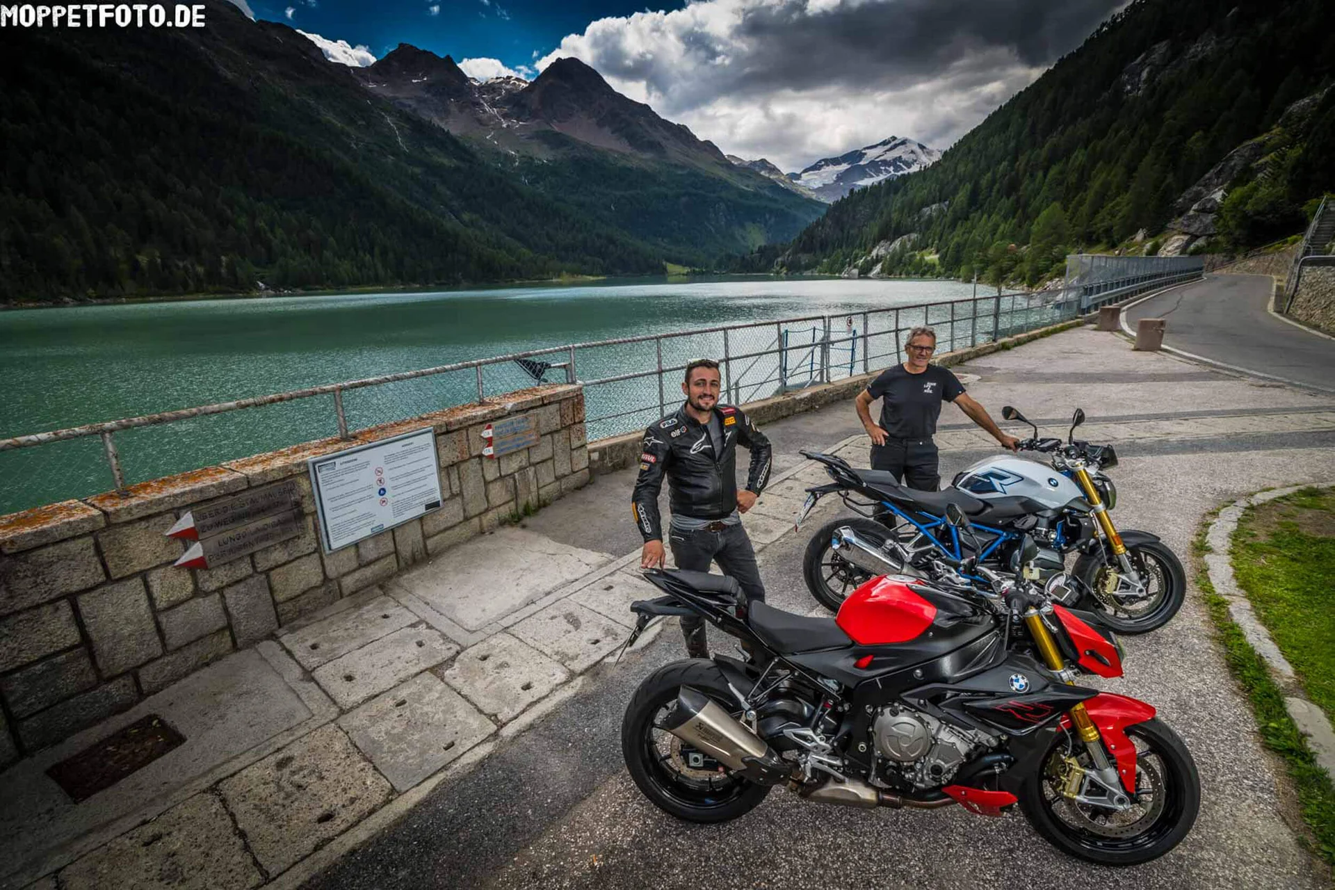 Motorradurlaub © Moppetfoto.de Zwei Männer mit Motorrädern an einem See mit Bergen im Hintergrund