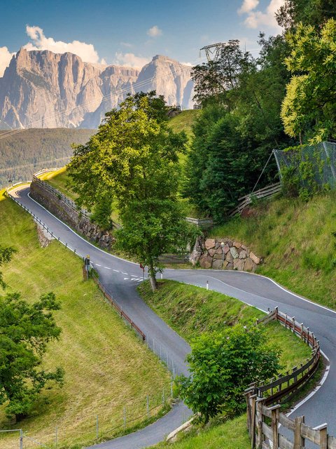 Motorradurlaub © Alexander Seger Motorradfahrer auf kurviger Bergstraße mit Bergen und Bäumen im Hintergrund