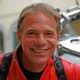 Motorradurlaub © Kurt Resch Steineggerhof Lächelnder Mann in rotem Shirt vor Motorrad