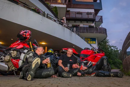 Bike & Ski Hotel Diana Karersee © Moppetfoto.de Three motorcyclists sitting on ground laughing with drinks near red motorcycles