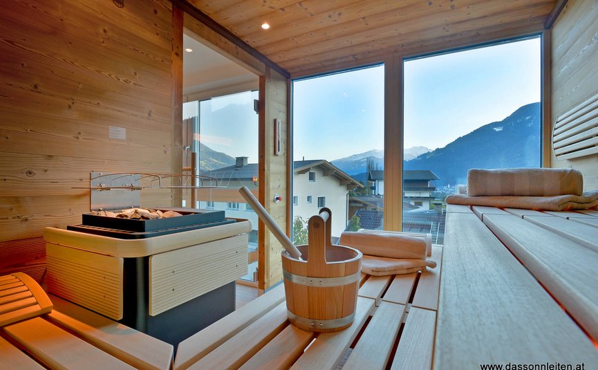 Hotel Sonnleiten *** Sauna with wooden benches and view of mountains and houses through glass windows