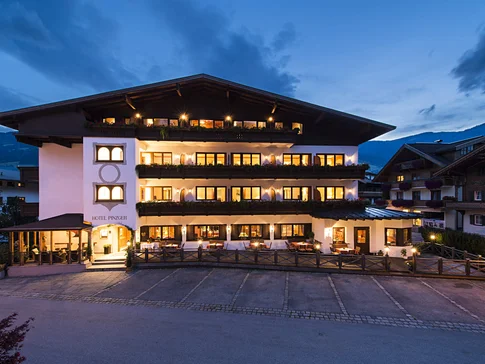 Hotel DER PINZGER © multi visual ART Illuminated hotel building at dusk in the mountains