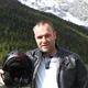 Motorradurlaub © compusol.it Mann mit Motorradhelm vor Berg- und Waldlandschaft