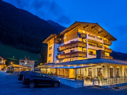 Hotel - Wirtshaus Lenz Lit mountain hotel at night with parked cars in front