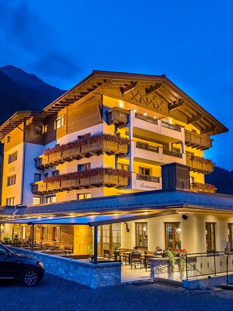 Motorradurlaub © Jones Art Beleuchtetes Hotel in den Bergen bei Nacht mit geparkten Autos