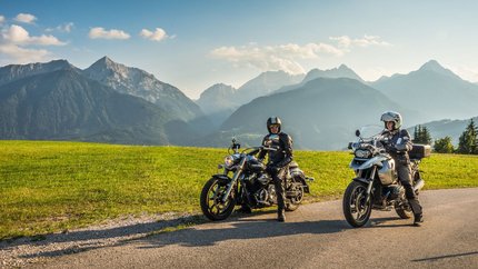 Kärnten © Moppetfoto.de Zwei Motorradfahrer auf Landstraße mit grünen Wiesen und Alpen im Hintergrund