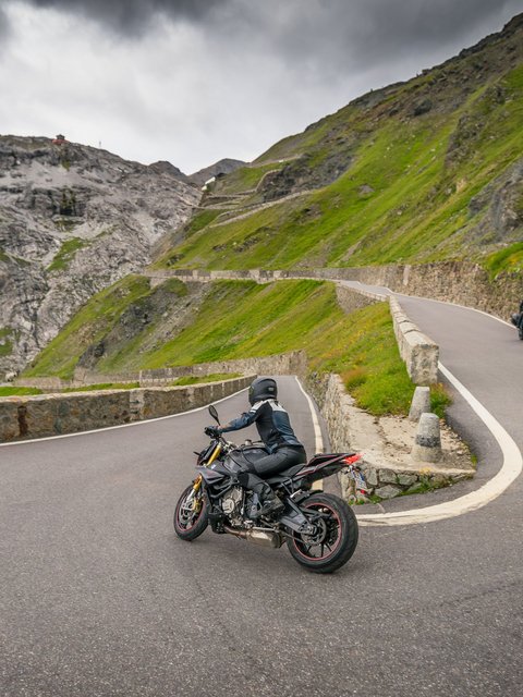 Motorradurlaub © Moppetfoto.de Motorradfahrer auf kurviger Bergstraße mit steilen Felswänden und Wolken