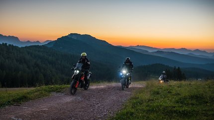 SalzburgerLand © Moppetfoto.de Drei Motorradfahrer fahren auf einem Bergweg bei Sonnenuntergang