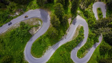 Tirol © Moppetfoto.de Luftaufnahme einer kurvigen Bergstraße mit Motorrädern und grüner Vegetation