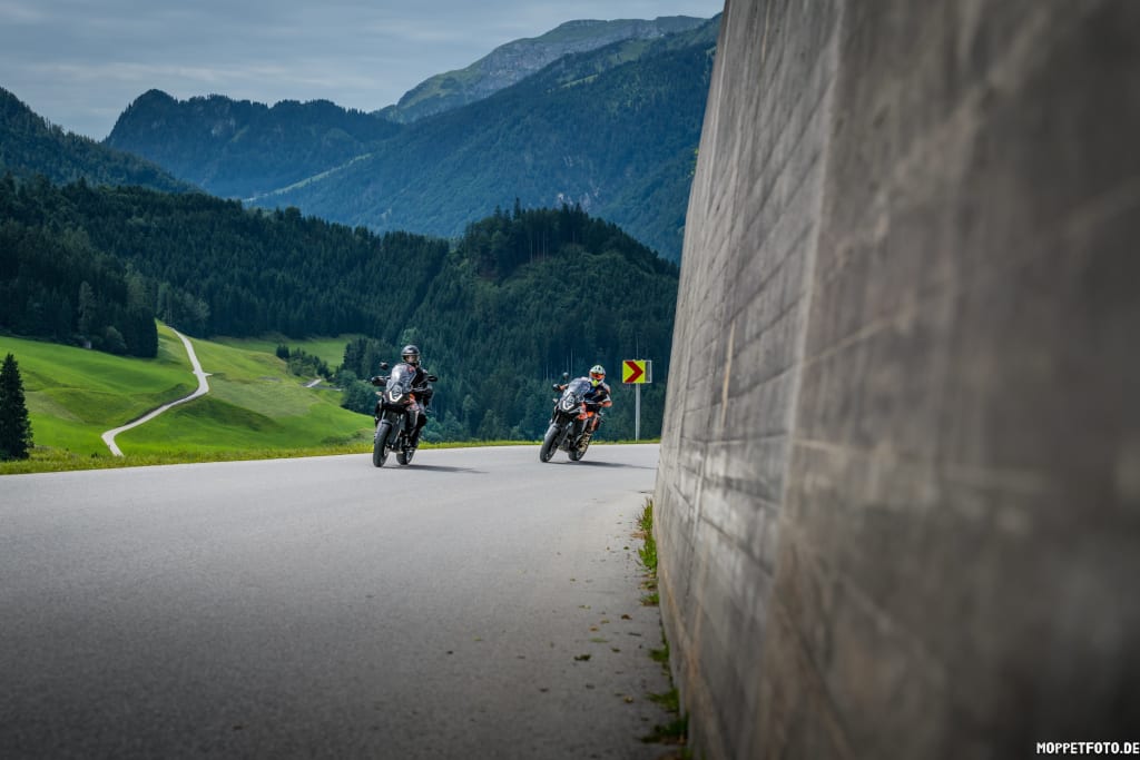 4 days motorcycle riding in Zillertal Two motorcyclists riding on a winding mountain road with forested hills