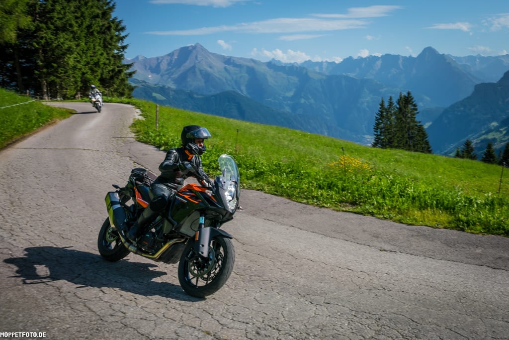 Motorcycle weekly package Motorcyclist riding on mountain road with Alps in the background